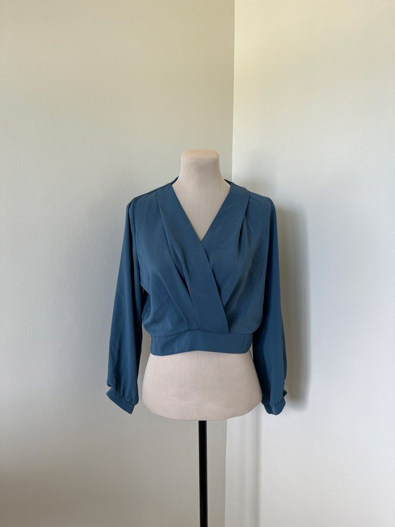Blue Wrap Crop Blouse Long Sleeves (Category: Longsleeves) located in Mandaluyong City. Submitted by bravedeer.020ad7 (Listing ID 1468362731, Image 1). Description: - Color: Solid Blue - Style: Wrap crop blouse with long sleeves - Features: Pleated neckline and fitted, clean-cut waistband - Fabric: Smooth and lightweight - Measurements: ~14 inches across the chest, ~17 inches from shoulder to hem - Condition: Excellent.