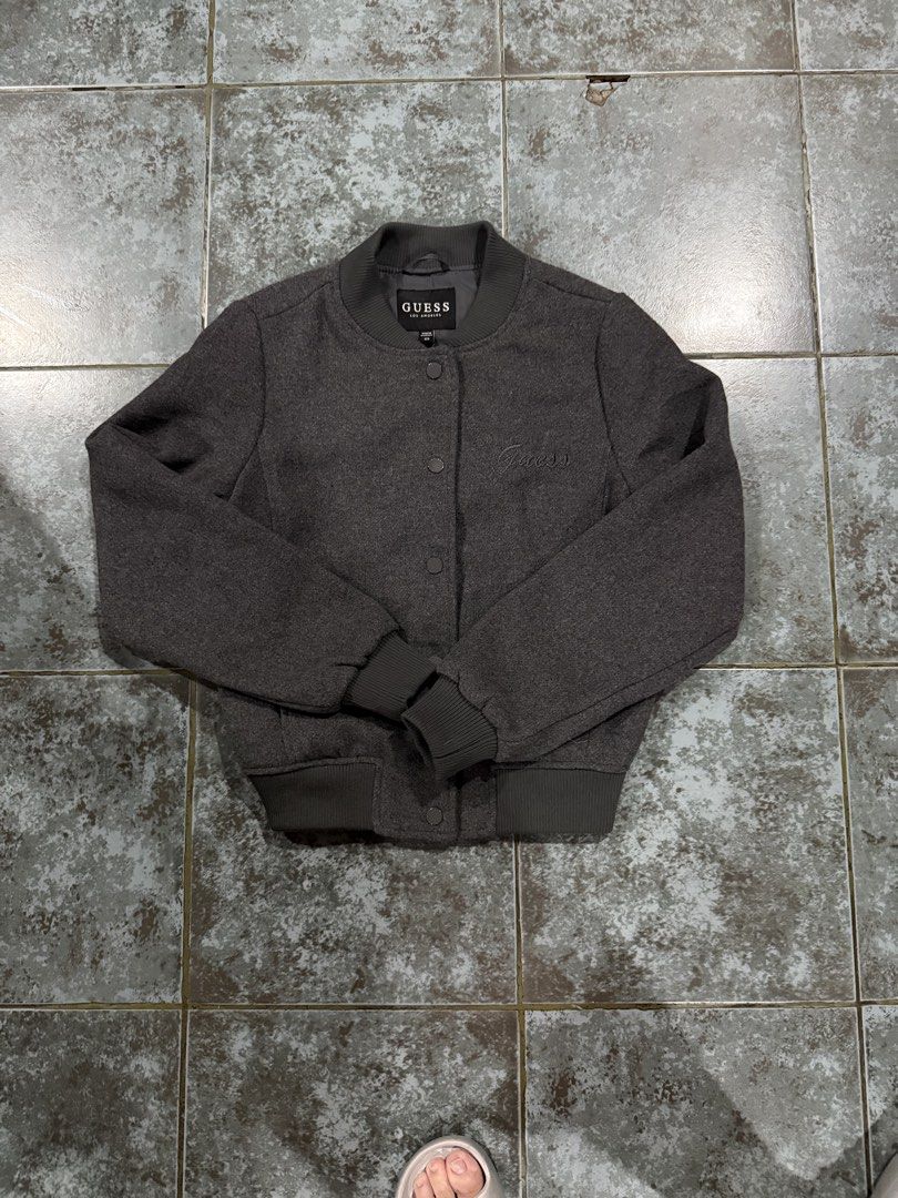 Bomber Jacket (Category: Coats, Jackets and Outerwear) located in Muntinlupa City. Submitted by avampaya (Listing ID 1468345802, Image 1). Description: - Brand: Guess - Color: Dark grey - Size: XS (can fit up to Small) - Closure: Snap button front - Details: Ribbed collar, cuffs, and hem, subtle embroidered logo on left chest, two side pockets - Just washed but never used.