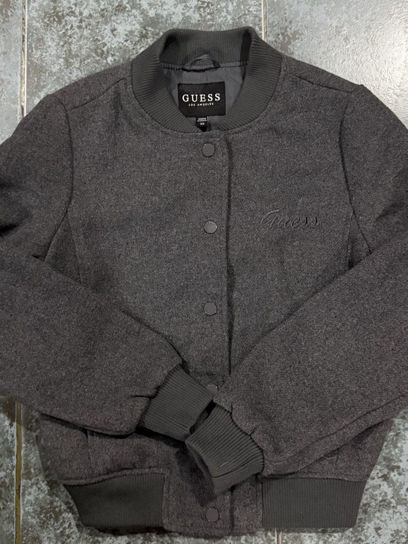 Bomber Jacket (Category: Coats, Jackets and Outerwear) located in Muntinlupa City. Submitted by avampaya (Listing ID 1468345802, Image 2). Description: - Brand: Guess - Color: Dark grey - Size: XS (can fit up to Small) - Closure: Snap button front - Details: Ribbed collar, cuffs, and hem, subtle embroidered logo on left chest, two side pockets - Just washed but never used.