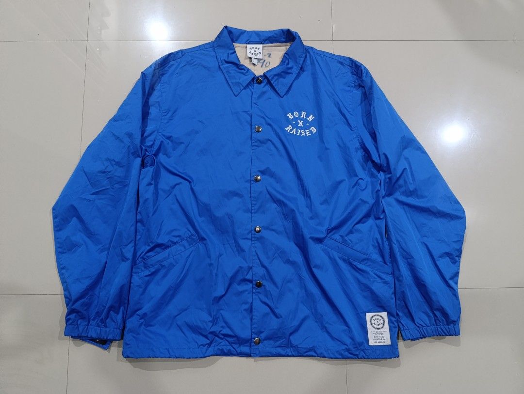 BORN X RAISED Coach Jacket (Category: Coats, Jackets and Outerwear) located in Davao. Submitted by idioticthrifter (Listing ID 1468463661, Image 1). Description: - Brand: Born X Raised - Style: Coach Jacket / Streetwear - Color: Bold Blue with contrasting inner lining - Size: Large (L) 24 width x 29 length - Closure: Snap button with zipper detail underneath - Details: Large white "On the turf, God loves the homies BXR" back graphic, small chest 