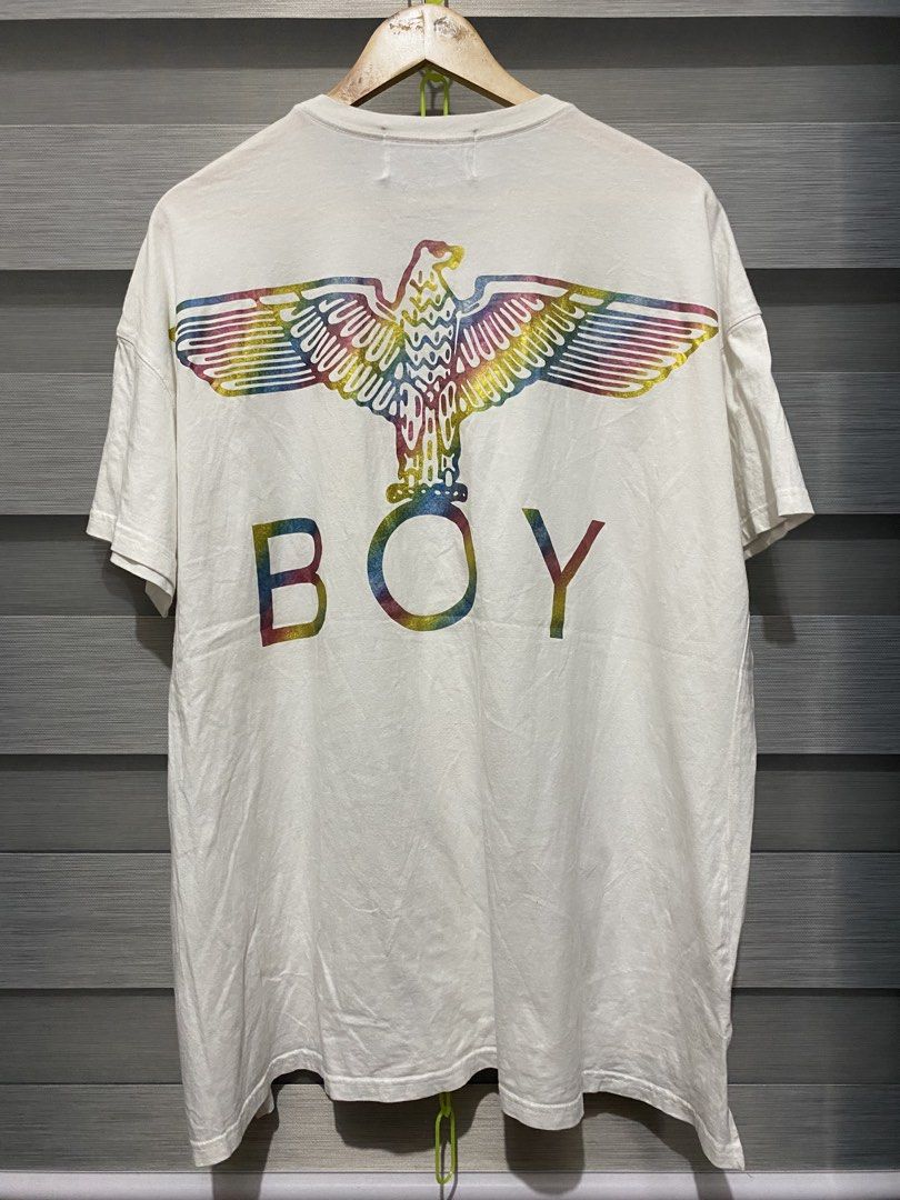 BOY London White Graphic Tee (Category: Shirts) located in Butuan. Submitted by nielben13 (Listing ID 1468412046, Image 2). Description: - Brand: BOY London (United Kingdom) - Color: Classic White - Design: Black shield logo patch on chest, metallic silver logo tag on hem, and large colorful rainbow eagle graphic with BOY lettering on the back - Fit: Relaxed fit with crew neck, short sleeves, and a slightly longer hem in the back - Condition: Exc