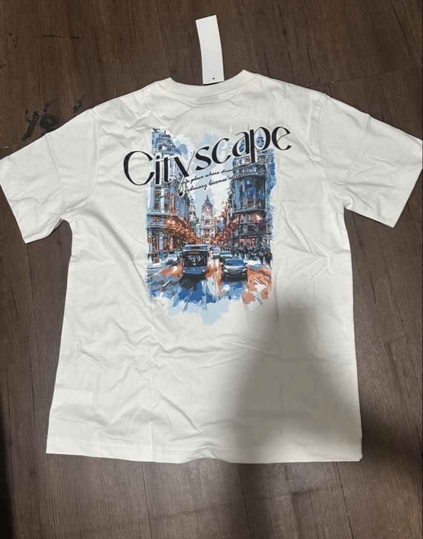 Brand new Penshoppe shirt (Category: Shirts) located in Subic. Submitted by declutterbyshit (Listing ID 1468306945, Image 3). Description: - Brand: Penshoppe - Style: Cityscape t-shirt - Color: White - Size: XS (27x20) fits to med (fits big) - Details: Short sleeves, classic crew neck, small front chest print, and large colorful city graphic with text on the back - Condition: Brand new with original store tag still attached.