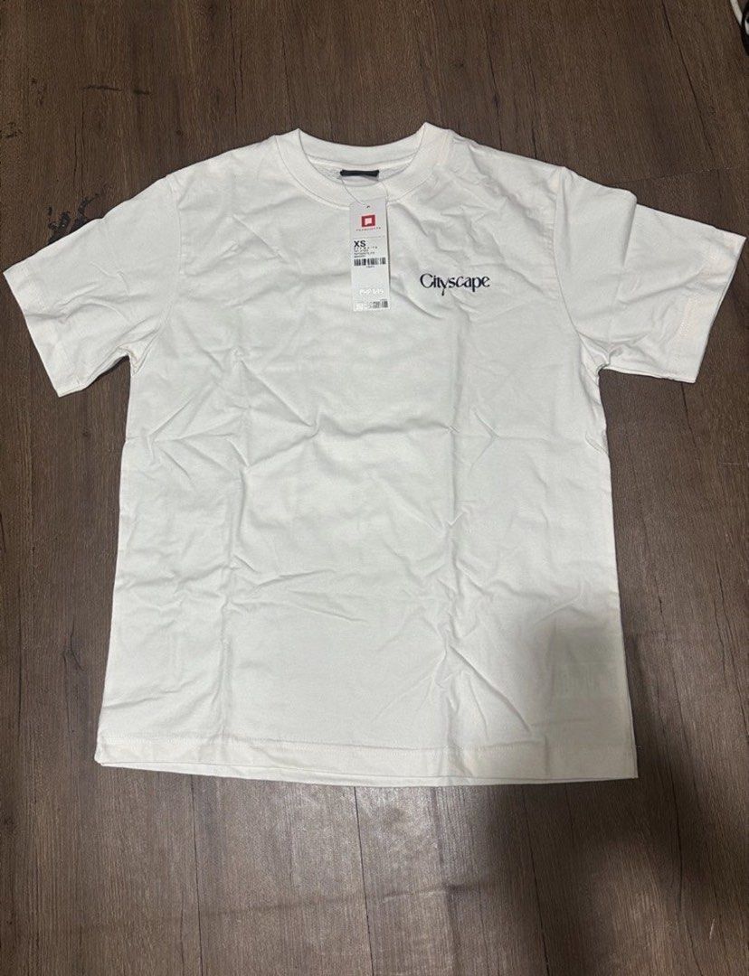 Brand new Penshoppe shirt (Category: Shirts) located in Subic. Submitted by declutterbyshit (Listing ID 1468306945, Image 2). Description: - Brand: Penshoppe - Style: Cityscape t-shirt - Color: White - Size: XS (27x20) fits to med (fits big) - Details: Short sleeves, classic crew neck, small front chest print, and large colorful city graphic with text on the back - Condition: Brand new with original store tag still attached.