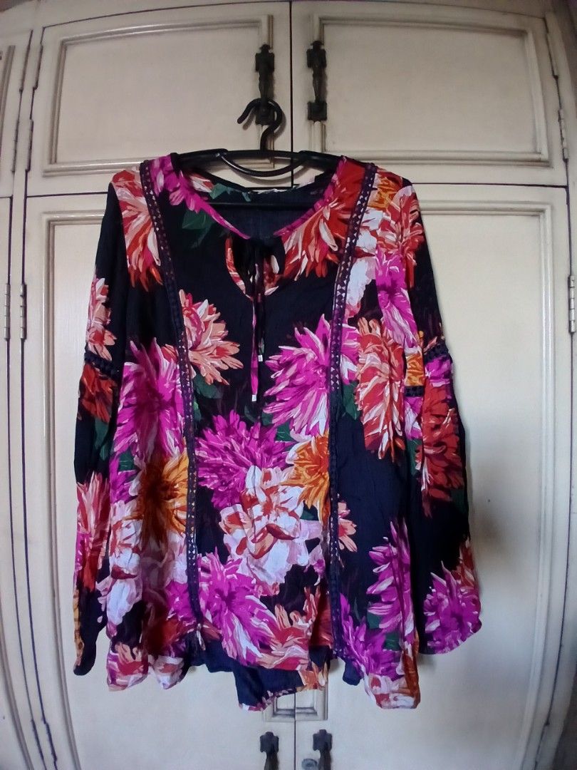 Bright Floral Blouse Lightweight Summer Style (Category: Blouses) located in Manila. Submitted by f.s_prelov3d (Listing ID 1468351837, Image 2). Description: - Color: Black base with vibrant pink, orange, and white floral print - Fit: Loose, flowy, and lightweight - Sleeves: Long sleeves - Details: Front tie closure with tassels, delicate lace trim along the front panel and shoulders - Perfect for: Casual wear, brunch dates, or effortless everyda