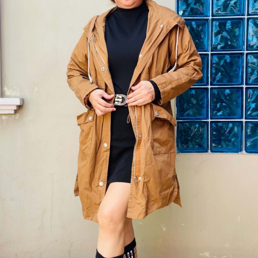 Brown hooded trench coat jacket with pockets (Category: Coats, Jackets and Outerwear) located in Bulacan. Submitted by fenph2021 (Listing ID 1468305069, Image 1). Description: - Color: Brown - Closure: Front zipper and snap buttons - Pockets: Two spacious side pockets - Hood: Adjustable with drawstrings - Length: Mid-length (covers past the hips) - Material: Lightweight and easy to layer over outfits.