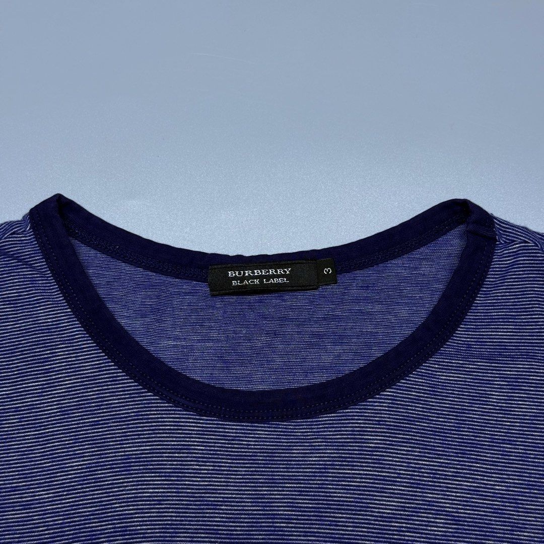 Burberry Black Label Blue Striped Ringer (Category: Luxury Apparel) located in Kabacan. Submitted by rags2penny.phl (Listing ID 1468336645, Image 3). Description: - Brand: Burberry Black Label - Color: Blue with thin horizontal stripes and dark navy collar/cuffs - Design: Large chest logo with unique floral pattern inside letters, plus small sleeve brand tag - Size: 3 (fits like a medium) - Material: Soft and lightweight 100% cotton - Condition: 