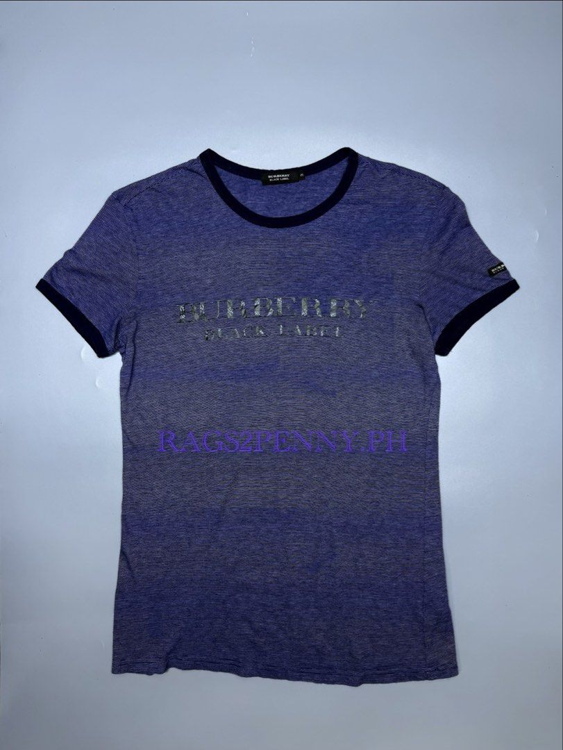 Burberry Black Label Blue Striped Ringer (Category: Luxury Apparel) located in Kabacan. Submitted by rags2penny.phl (Listing ID 1468336645, Image 1). Description: - Brand: Burberry Black Label - Color: Blue with thin horizontal stripes and dark navy collar/cuffs - Design: Large chest logo with unique floral pattern inside letters, plus small sleeve brand tag - Size: 3 (fits like a medium) - Material: Soft and lightweight 100% cotton - Condition: 