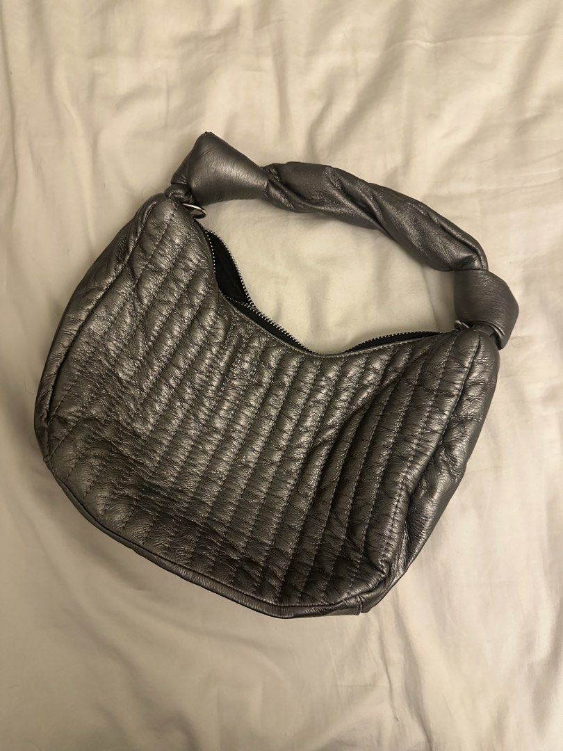 Cachellie Metallic Silver Quilted Shoulder Bag (Category: Luxury Bags & Wallets) located in Pasig City. Submitted by cosmicjuice08 (Listing ID 1468405962, Image 1). Description: - Brand: Cachellie - Color: Metallic silver with vertical quilting - Handle: Unique twisted design with knotted ends - Closure: Secure top zip closure - Interior: Black fabric lining with a slip pocket and brand tag - Size: Compact, perfect for daily essentials A lightwei
