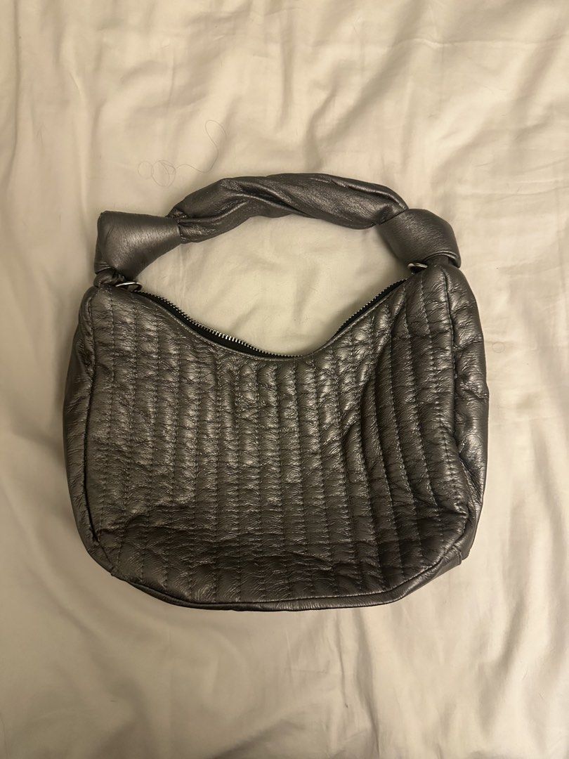 Cachellie Metallic Silver Quilted Shoulder Bag (Category: Luxury Bags & Wallets) located in Pasig City. Submitted by cosmicjuice08 (Listing ID 1468405962, Image 2). Description: - Brand: Cachellie - Color: Metallic silver with vertical quilting - Handle: Unique twisted design with knotted ends - Closure: Secure top zip closure - Interior: Black fabric lining with a slip pocket and brand tag - Size: Compact, perfect for daily essentials A lightwei
