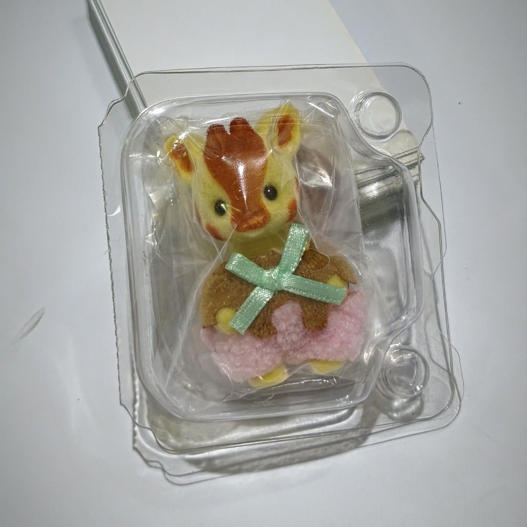 Calico Critters Giraffe Baby (Category: Figurines & Statues) located in Manila. Submitted by abbey.lee (Listing ID 1468482329, Image 1). Description: - Authentic Calico Critters Giraffe baby figure - Soft and fuzzy flocked texture in yellow and brown - Wears an adorable pink fluffy outfit - Holding a cute brown treat tied with a light green ribbon - Brand new, kept securely inside original clear plastic packaging.