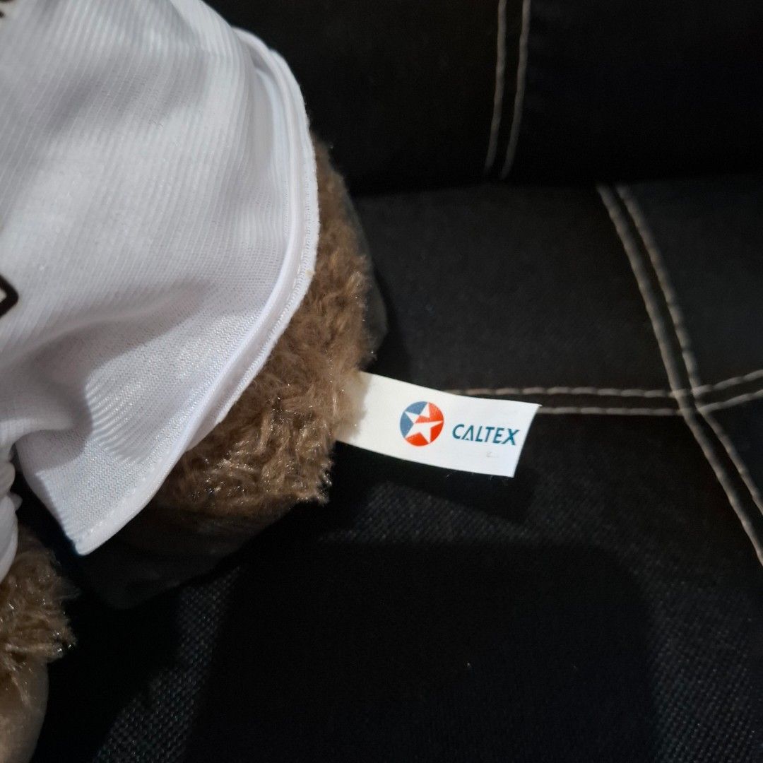 Caltex Teddy Bear (Category: Plushies & Soft Toys) located in Baliuag. Submitted by ahgashop. (Listing ID 1468297417, Image 3). Description: - Caltex Teddy Bear - Dressed in a white button-up shirt with 'Enjoy The Journey' print and Caltex star logo pocket - Features cute embroidered star details on the footpads - Perfect for collectors and gift ideas.