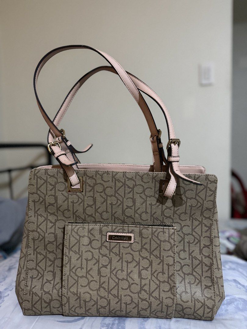 Calvin Klein Monogram Tote Bag Brown and Pink (Category: Tote Bags) located in Tacloban City. Submitted by chrischanah (Listing ID 1468477775, Image 1). Description: - Authentic Calvin Klein tote bag in a stylish brown monogram print - Accented with chic pink straps, trim, and elegant gold hardware - Organized interior featuring multiple compartments and a secure zipped middle section - Convenient exterior slip pocket on the front for easy access