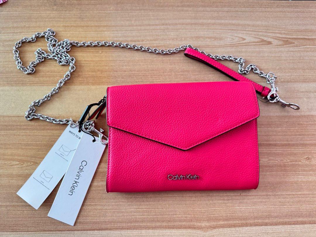 Calvin Klein Pink Crossbody Bag (Category: Cross-body Bags) located in Valenzuela. Submitted by declutterlangpo (Listing ID 1468298903, Image 2). Description: - Brand new with original tags attached (MSRP $148.00) - Eye-catching bright pink color with a chic silver chain strap - Organized interior with multiple compartments, card slots, and a middle zipped pocket - Tag code: H2ER5J3 - Flaw note: Minor paint chipping at the bottom corner edge (pri
