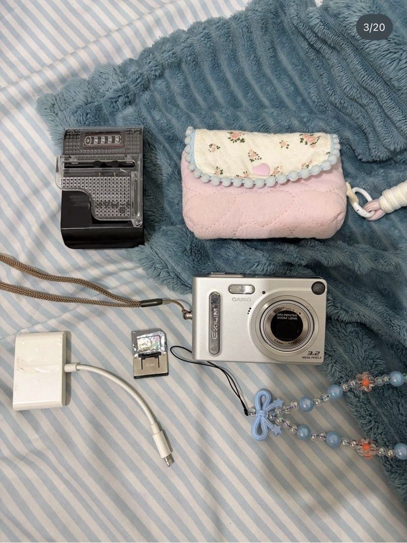 Casio Exilim 3.2 Mega Pixels Digital Camera Bundle (Category: Cameras) located in Magsingal. Submitted by shopbymariyaa (Listing ID 1468389451, Image 3). Description: - Tested and fully working Casio Exilim compact digital camera (Silver, 3.2 MP with SMC Pentax zoom lens) - Perfect for achieving that authentic early 2000s Y2K aesthetic - Complete bundle includes a padded pink floral pouch and a beaded wrist strap - Includes charging dock, battery