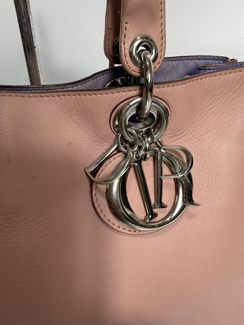 CD (Category: Luxury Bags & Wallets) located in Dasmarinas. Submitted by arjalaph (Listing ID 1468494331, Image 3). Description: - Brand: Christian Dior - Color: Soft pink exterior, purple interior - Hardware: Silver-tone with iconic dangling Dior charm - Closure: Button closure - Interior: Purple leather lining with convenient slip pockets - Handles: Dual top handles for easy carrying.