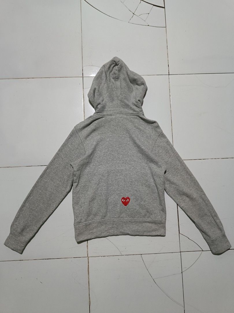 CDG PLAY x Nike Grey Pullover Hoodie (Category: Coats, Jackets and Outerwear) located in Barotac Nuevo. Submitted by gray101 (Listing ID 1468406723, Image 2). Description: - Brand: Comme des Garçons Play x Nike - Color: Grey - Size/Condition: Clean piece, worn only a few times - Design: Embroidered red heart logo near the front pocket - Graphics: Black swoosh graphic printed on the lower front - Features: Drawstring hood with white cords, kangaro