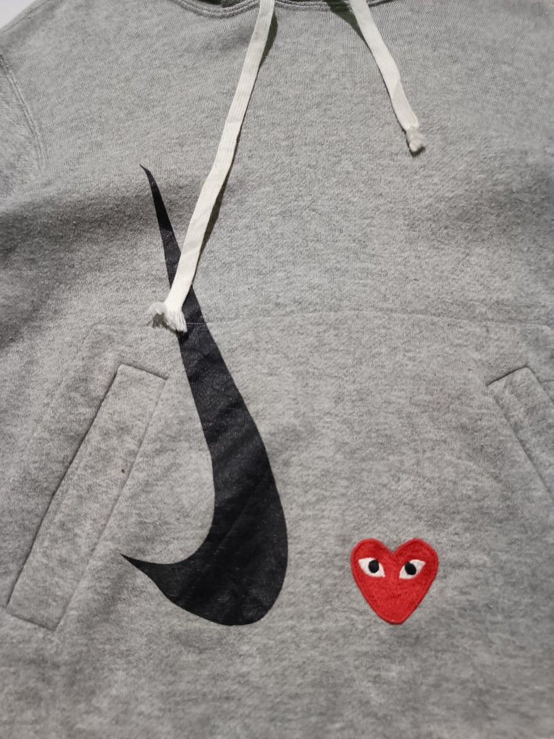 CDG PLAY x Nike Grey Pullover Hoodie (Category: Coats, Jackets and Outerwear) located in Barotac Nuevo. Submitted by gray101 (Listing ID 1468406723, Image 3). Description: - Brand: Comme des Garçons Play x Nike - Color: Grey - Size/Condition: Clean piece, worn only a few times - Design: Embroidered red heart logo near the front pocket - Graphics: Black swoosh graphic printed on the lower front - Features: Drawstring hood with white cords, kangaro