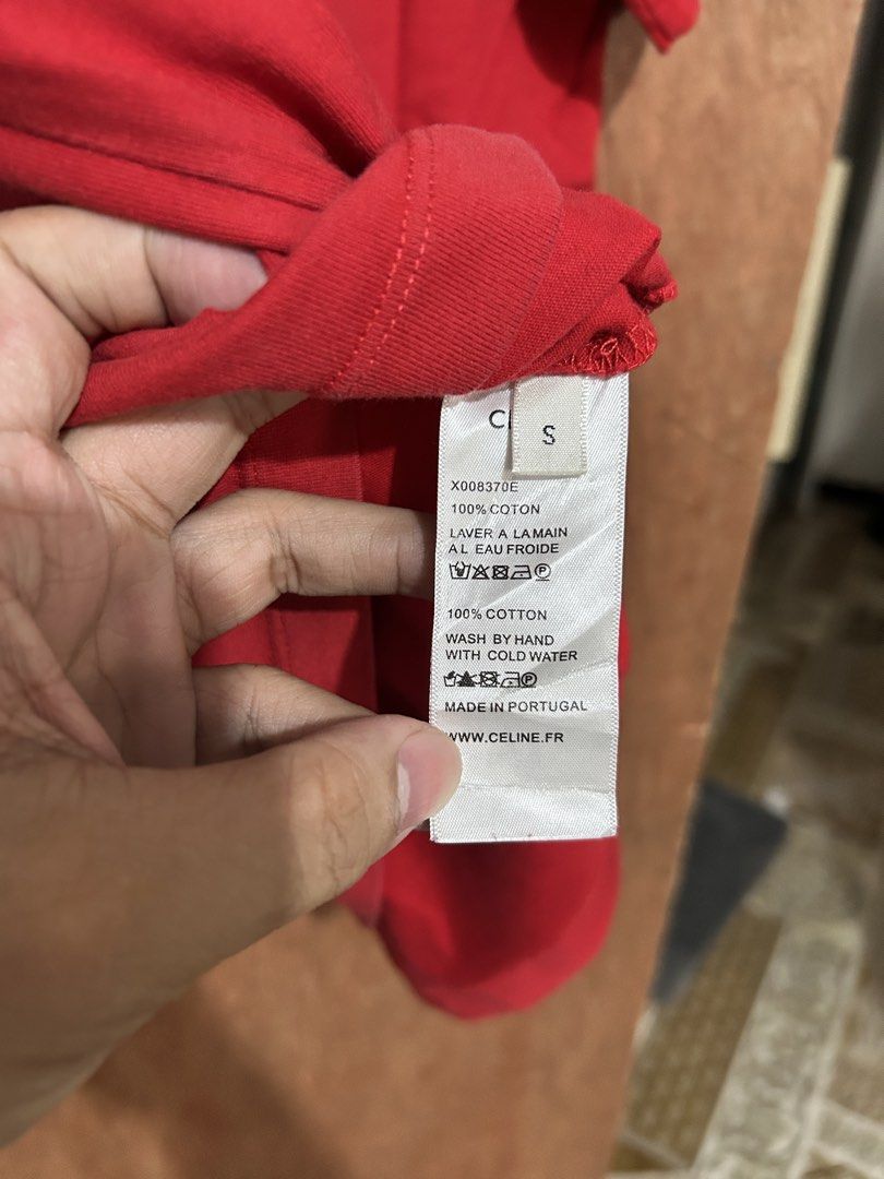 Celine Red T-shirt (Category: Shirts) located in Davao. Submitted by orbetaarch23339 (Listing ID 1468422063, Image 3). Description: - Brand: Celine - Color: Red - Size: S - Material: 100% Cotton (Made in Portugal) - Design: White gothic C logo on chest, large Celine text on back - Condition: Clean overall with flawless prints - Care: Hand wash with cold water only.