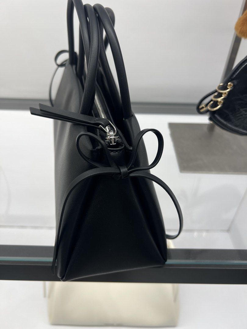 Charles & Keith Black Structured Shoulder Bag (Category: Shoulder Bags) located in Lipa City. Submitted by thyra06 (Listing ID 1468340461, Image 3). Description: - Brand: Charles & Keith - Color: Classic Black with silver-tone hardware - Design: Structured trapezoid shape with a clean matte finish - Features: Top zip closure, sturdy double handles, and an adorable ribbon detail tied on the side strap - Condition: Excellent, well-maintained - Perf