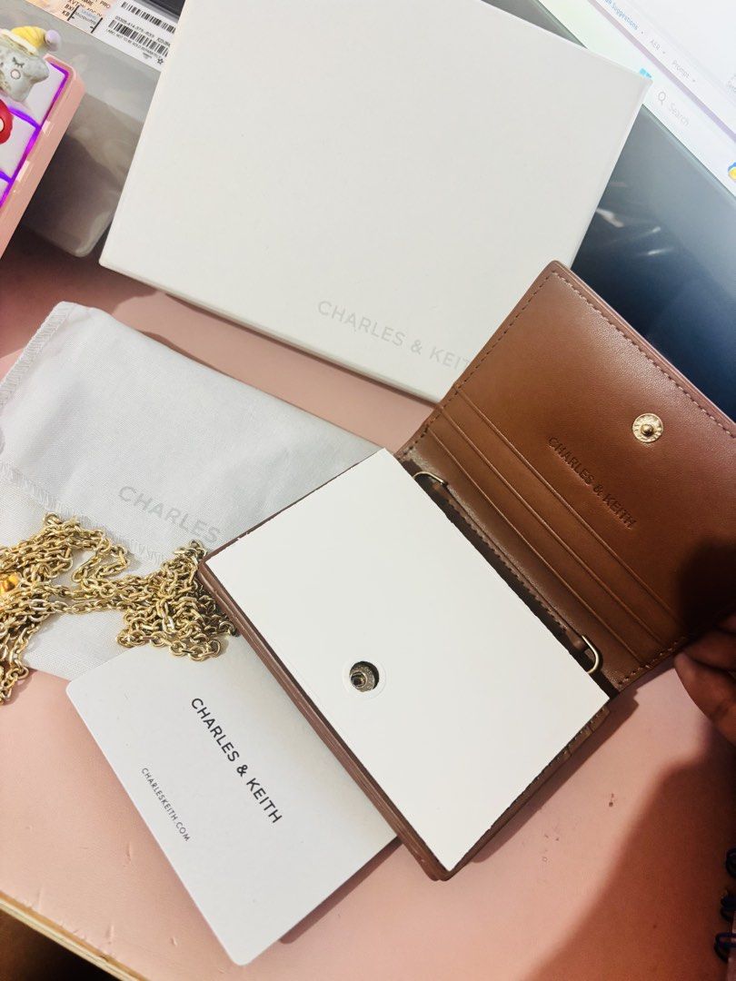Charles & Keith Brown Wallet with Chain (Category: Wallets & Card holders) located in Cavite. Submitted by gianflores (Listing ID 1468471399, Image 2). Description: - Brand: Charles & Keith - Color: Rich brown leather - Versatile: Includes a gold chain strap to convert into a mini crossbody bag - Features: Interior card slots and secure snap button closure - Condition: Brand new, never used, with all packaging intact - Inclusions: Original box, d
