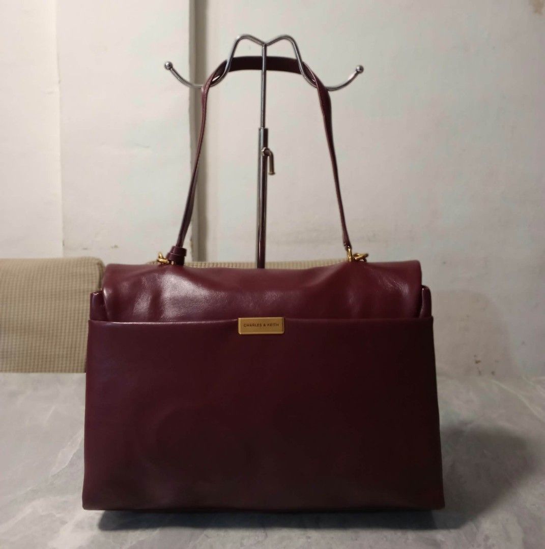 Charles & Keith Burgundy Shoulder Bag (Category: Shoulder Bags) located in Manila. Submitted by cosmiccloud-9236 (Listing ID 1468478498, Image 2). Description: - Brand: Charles & Keith - Color: Rich burgundy with premium gold-tone hardware - Closure: Secure front flap with twist-lock mechanism - Straps: Comes with fixed shoulder straps and a detachable long crossbody strap - Pockets: Convenient exterior back slip pocket with metallic logo plate -
