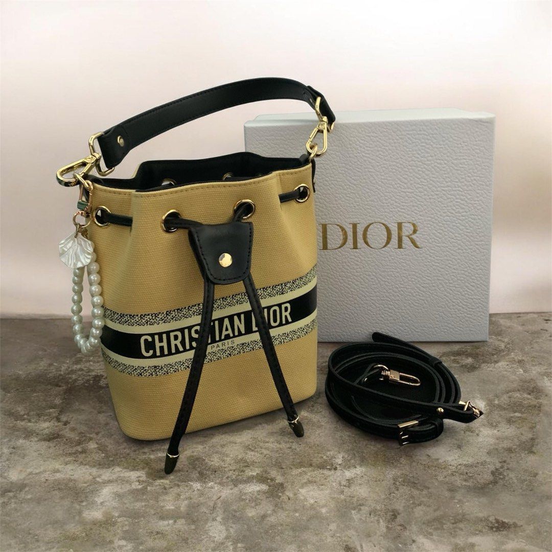 Christian Dior Bucket Bag with Box and Strap (Category: Luxury Bags & Wallets) located in Manila. Submitted by meimei6767 (Listing ID 1468290364, Image 1). Description: * Brand: Christian Dior * Type: Mini Bucket Bag / Crossbody Bag * Color: Tan/Beige & Black * Material: Canvas with contrasting trim * Gold-tone hardware * Drawstring closure * Adjustable/removable shoulder strap * Decorative pearl & leaf charm .