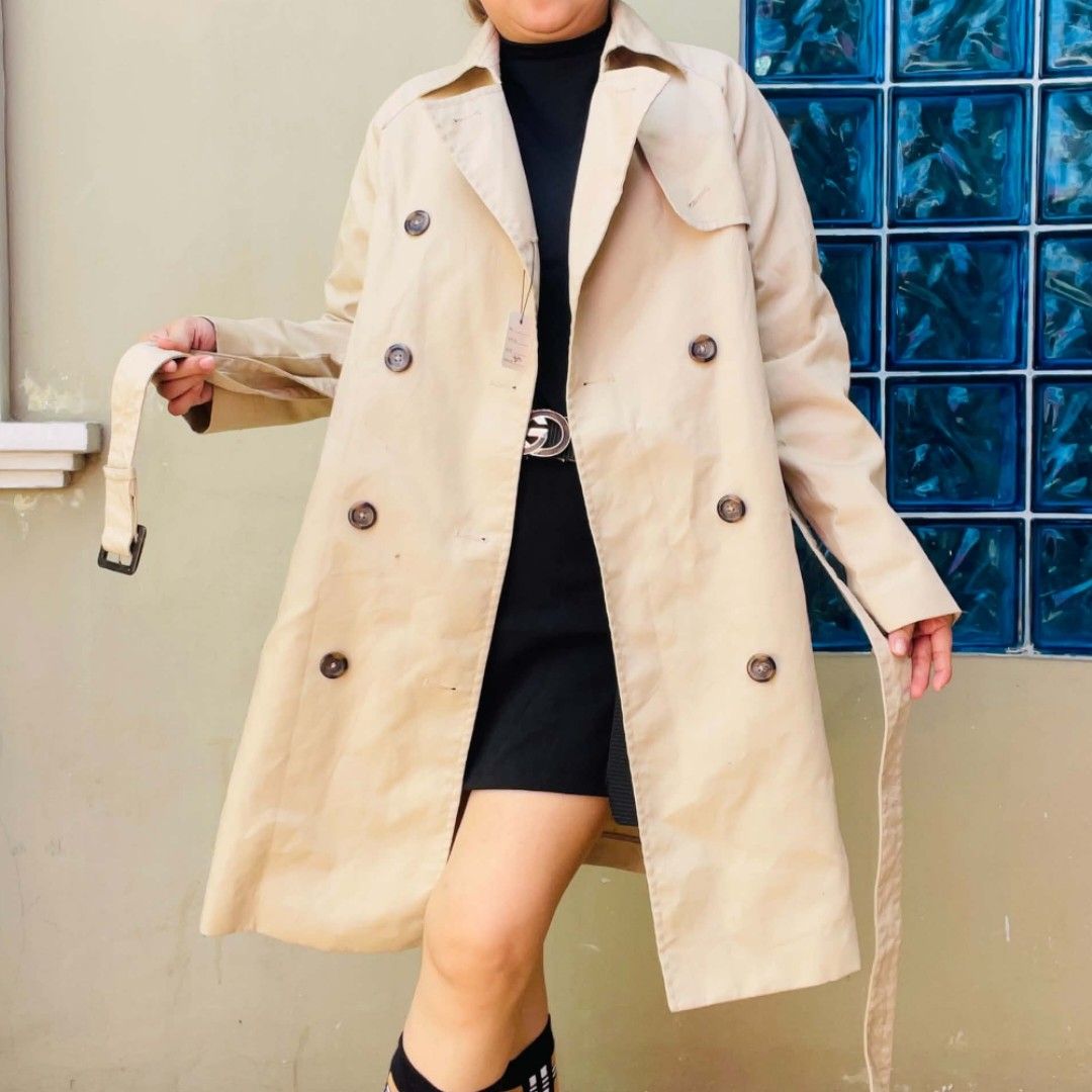Classic Beige Double-Breasted Trench Coat with Belt (Category: Coats, Jackets and Outerwear) located in Bulacan. Submitted by fenph2021 (Listing ID 1468304899, Image 1). Description: - Classic beige lightweight trench coat - Double-breasted button front closure - Matching adjustable tie belt at the waist - Stylish notched lapels and long sleeves brandnew with tags - Flattering mid-length style hitting above the knee - Perfect transitional outerwe