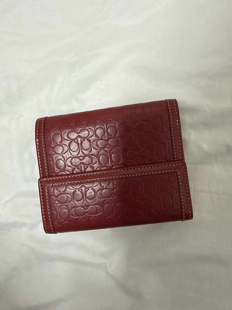 Coach Red Signature Embossed Leather Wallet (Category: Wallets & Card holders) located in Santa Rosa. Submitted by decluttering_. (Listing ID 1468499741, Image 2). Description: - Authentic red leather Coach wallet with debossed signature C pattern - Elegant white contrast stitching and silver-tone hardware - Secure snap button closure on the front flap - Light tan leather interior with multiple card slots and cash compartments - Features a subtle