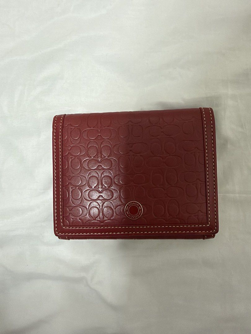 Coach Red Signature Embossed Leather Wallet (Category: Wallets & Card holders) located in Santa Rosa. Submitted by decluttering_. (Listing ID 1468499741, Image 1). Description: - Authentic red leather Coach wallet with debossed signature C pattern - Elegant white contrast stitching and silver-tone hardware - Secure snap button closure on the front flap - Light tan leather interior with multiple card slots and cash compartments - Features a subtle