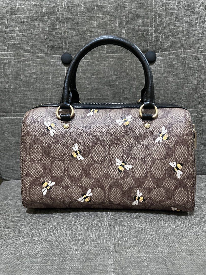Coach Rowan Satchel Bag (Category: Luxury Bags & Wallets) located in Manila. Submitted by zencat.93bfa9 (Listing ID 1468437323, Image 2). Description: - Coach signature satchel with playful bee print details - Brown coated canvas body with stylish black leather handles, trim, and detachable crossbody strap - Features secure top zip closure, front zip pocket, and elegant gold-tone hardware - Includes interior creed tag and signature Coach hangtag.