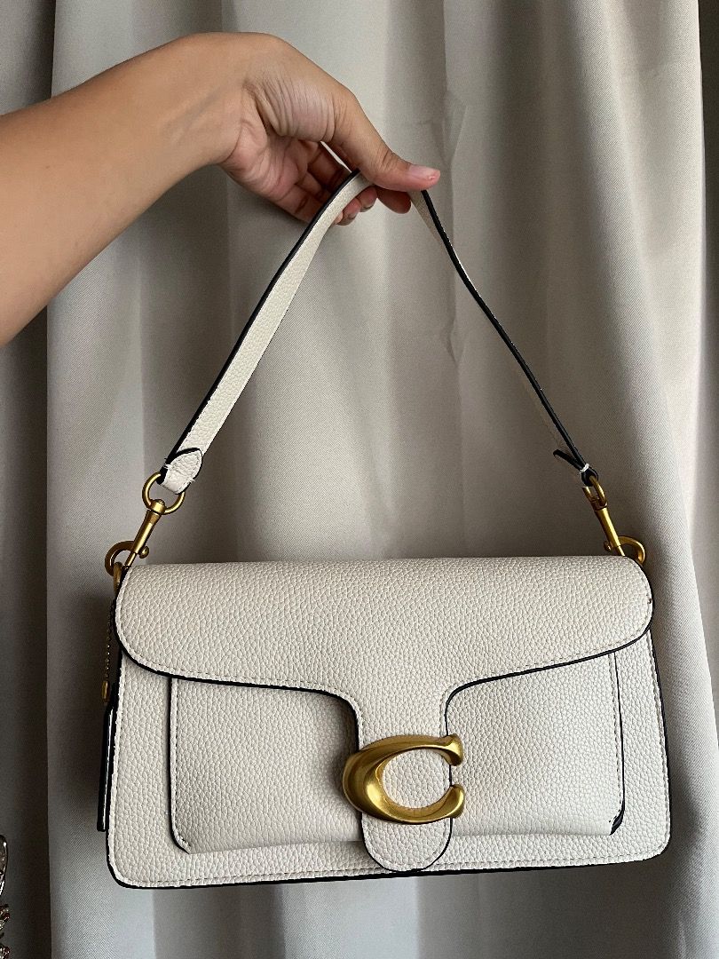 Coach Tabby Shoulder Bag White Brass Hardware (Category: Shoulder Bags) located in Caloocan City. Submitted by safemountain.0b3a05 (Listing ID 1468394426, Image 1). Description: - Authentic Coach Tabby shoulder bag in classic white pebbled leather - Stunning antique brass 'C' closure and hardware - Soft tan suede fabric interior lining - Organized interior with multiple compartments and a central zipped divider - Clean, structured silhouette perf