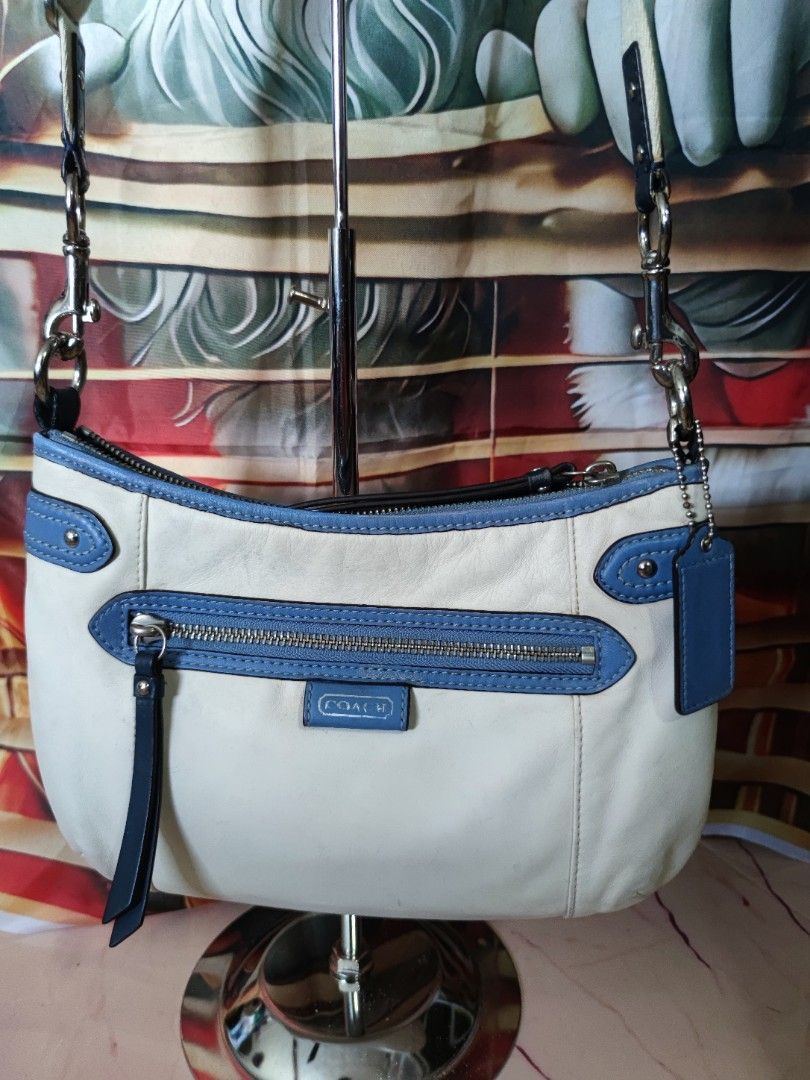Coach White and Blue Leather Shoulder Bag (Category: Luxury Bags & Wallets) located in Dagupan City. Submitted by jhazrightshop (Listing ID 1468474392, Image 2). Description: - Authentic Coach shoulder bag in white leather with blue trim - Convenient front zipped pocket with a leather pull tab - Includes a matching blue leather hangtag on a beaded chain - Adjustable strap with sleek silver hardware - Detailed interior zipper pull with clear Coach