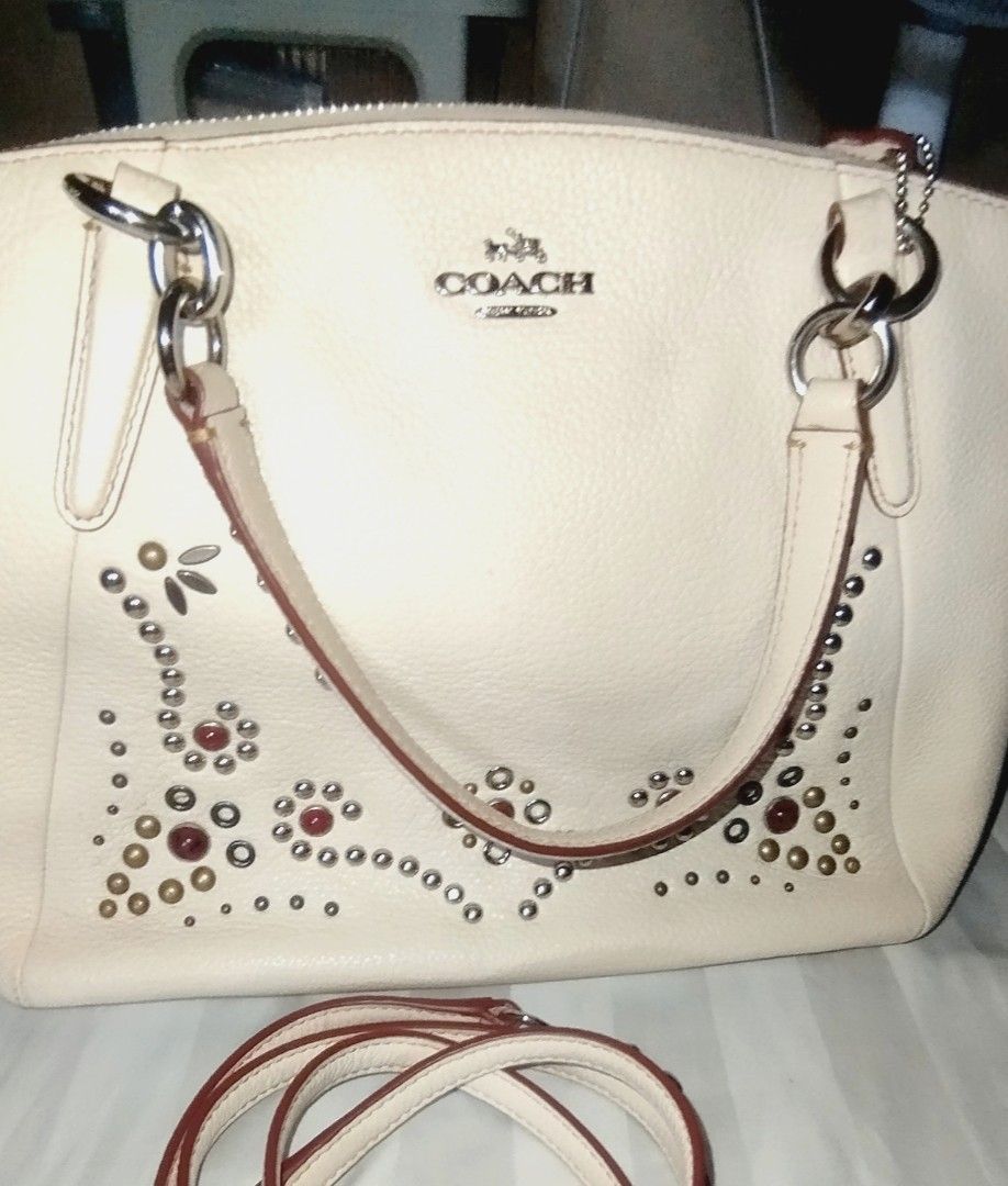 Coach White Leather Studded Satchel Handbag (Category: Cross-body Bags) located in Manila. Submitted by lene48 (Listing ID 1468392241, Image 2). Description: - Brand: Coach - Style: Leather Satchel / Shoulder Bag - Color: Off-white with silver hardware - Details: Metal stud accents on the lower front and stamped Coach logo - Interior: Brown fabric lining with slip pockets and one zip pocket - Straps: Twin carry handles and a detachable shoulder s