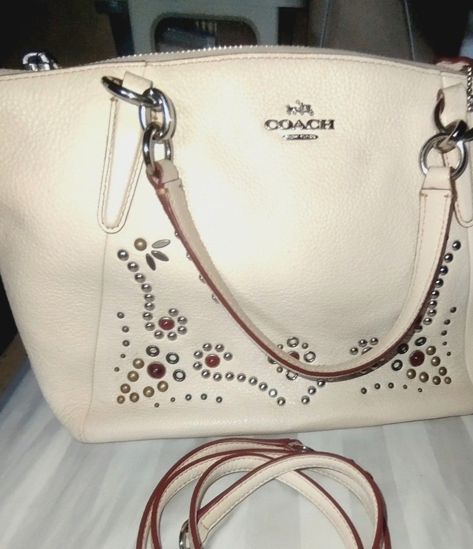 Coach White Leather Studded Satchel Handbag (Category: Cross-body Bags) located in Manila. Submitted by lene48 (Listing ID 1468392241, Image 1). Description: - Brand: Coach - Style: Leather Satchel / Shoulder Bag - Color: Off-white with silver hardware - Details: Metal stud accents on the lower front and stamped Coach logo - Interior: Brown fabric lining with slip pockets and one zip pocket - Straps: Twin carry handles and a detachable shoulder s