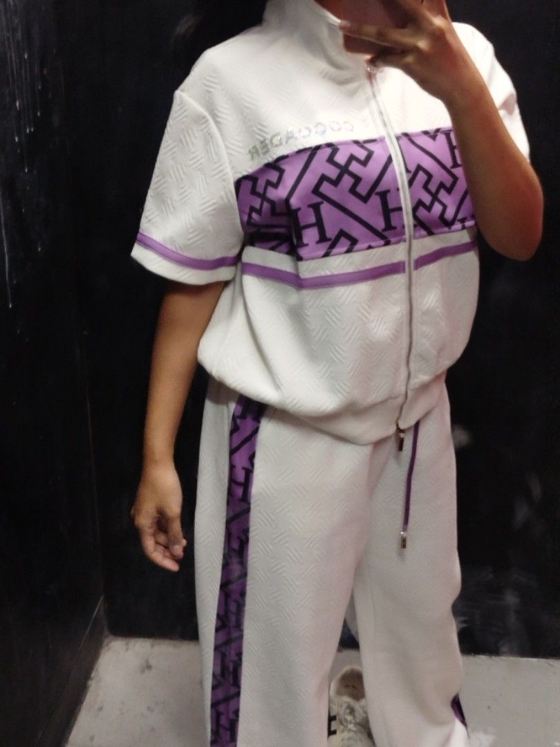 Coco Ader White and Purple Tracksuit Set (Category: Sets or Coordinates) located in Quezon City. Submitted by cuteitemsonlyyy (Listing ID 1468415314, Image 2). Description: - Brand: Coco Ader - Color: White with purple and black geometric 'H' letter pattern panels - Top: Short sleeve zip-up track jacket with high collar and sparkly rhinestone zipper pull - Bottoms: Matching wide-leg trousers with stylish side stripe details - Fabric: Textured mat