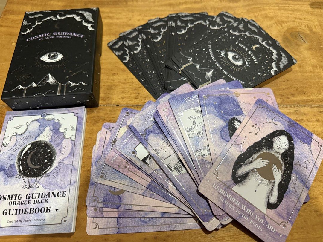 Cosmic Guidance Oracle Deck by Annie Tarasova (Category: Art & Prints) located in Quezon City. Submitted by wiya88 (Listing ID 1468430680, Image 1). Description: - Authentic Cosmic Guidance Oracle Deck by Annie Tarasova - Includes sturdy black storage box and matching purple and white guidebook - Complete set of cards with stunning purple watercolor fronts and celestial illustrations - Backs feature sleek black design with silver foil eye and mou