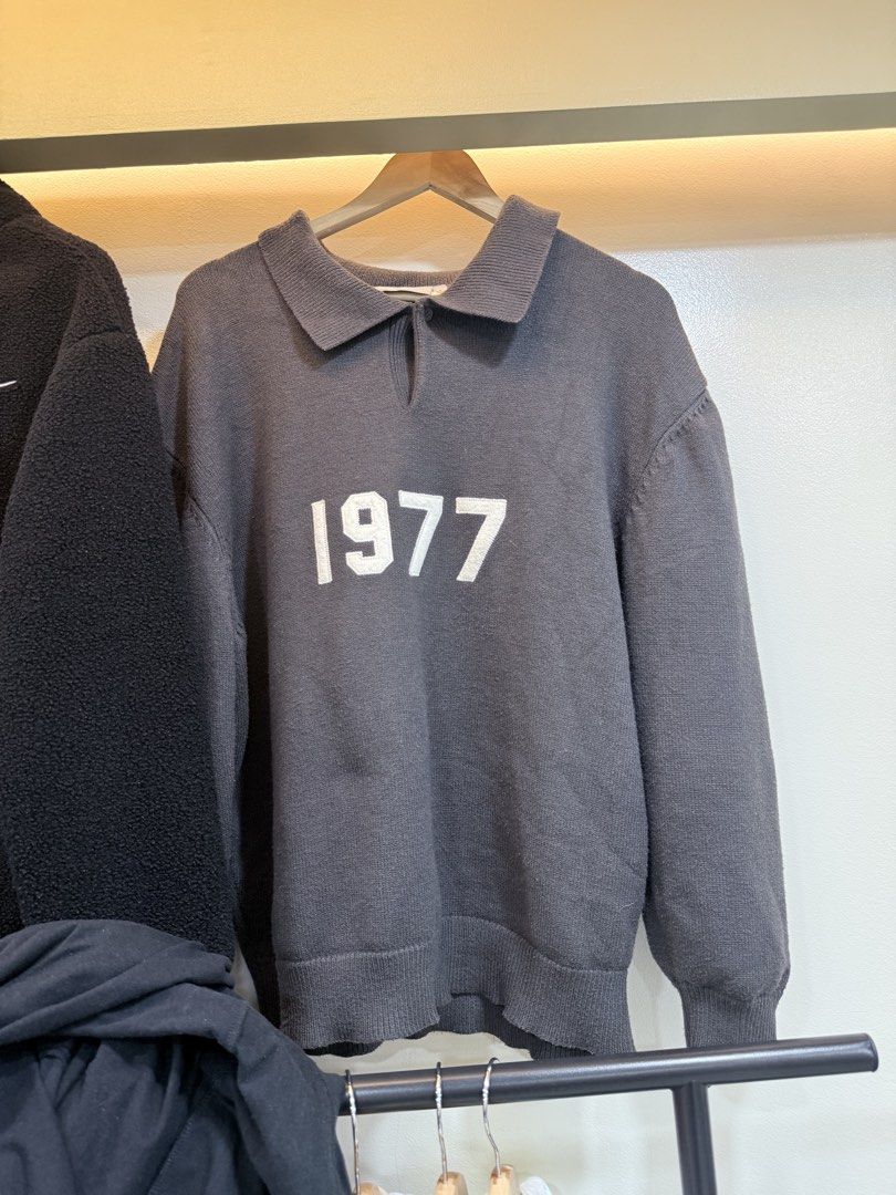 Dark Grey 1977 Knit Polo Sweater (Category: Coats, Jackets and Outerwear) located in Quezon City. Submitted by nichole12 (Listing ID 1468461629, Image 1). Description: - Color: Dark grey - Design: Embroidered '1977' on the chest, collared neckline with buttonless slit - Features: Long sleeves, ribbed cuffs and hem, thick knit material - Fit: Comfortable, ideal layering piece for cooler weather - Condition: Clean and well-maintained.