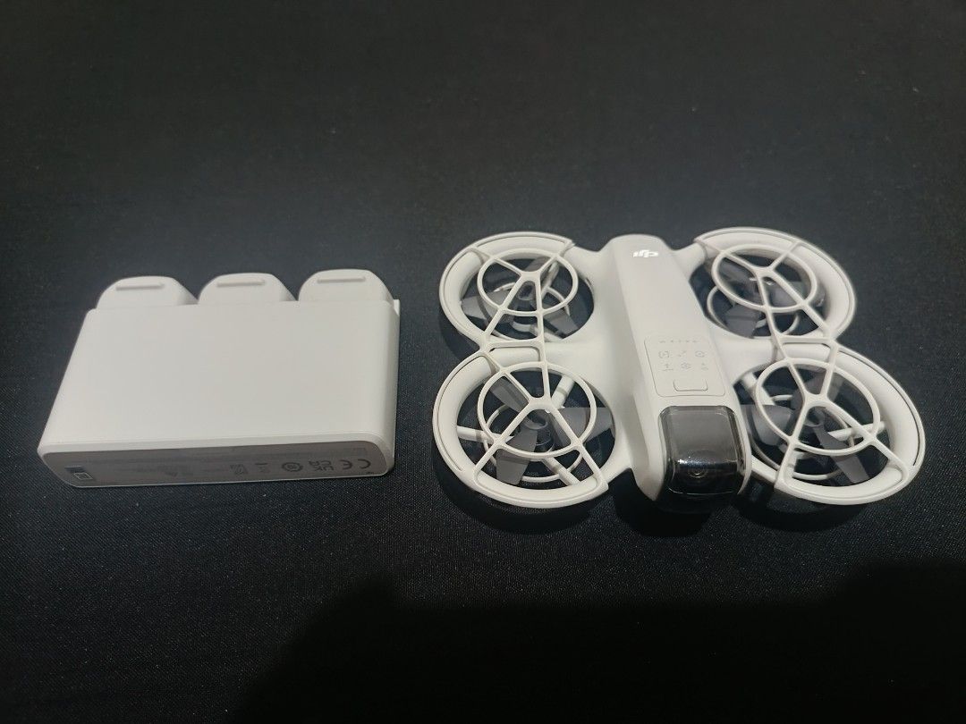 DJI Neo Drone with Battery Charging Hub (Category: Drones) located in Quezon City. Submitted by arisantonio26 (Listing ID 1468427546, Image 2). Description: - Model: DJI Neo (White, pristine condition, zero scratches) - Safety: Built-in propeller guards for indoor and outdoor flying - Power: Includes multi-battery charging dock (holds 3 batteries) - Ideal For: Quick aerial shots, content creators, and vloggers - Condition: Fully operational and r