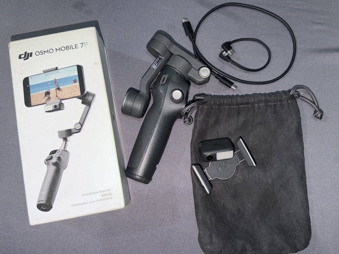 DJI Osmo Mobile 7P Smartphone Stabilizer Gimbal (Category: Gimbals & Stabilizers ) located in Quezon City. Submitted by jpfinds (Listing ID 1468436305, Image 1). Description: DJI Osmo Mobile 7P smartphone stabilizer. Includes original box, pouch, magnetic phone clamp, built-in fill light/tracker module, and charging cables. Everything powers on and functions properly. Minimal wear on the handle grip, screen lights up clearly. Great setup for smoo