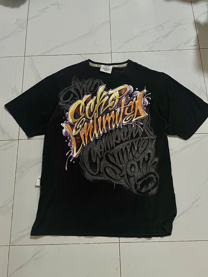Ecko Untd graffiti (Category: Formal Shirts) located in Caloocan City. Submitted by whirshie (Listing ID 1468314765, Image 1). Description: - Brand: Ecko Unltd - measurements: 21.5x28-29 - Color: Black - Size: Medium - Material: 100% Cotton - Design: Large graffiti-style front print in gold, orange, and purple with iconic rhino logo - Details: Branded tape inside the collar - Condition: Excellent pre-loved condition - Perfect for streetwear and c