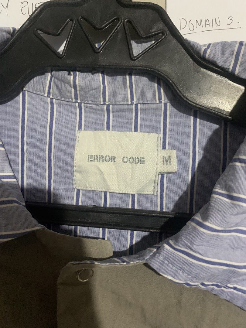 ERROR CODE Colorblock Striped Short Sleeve Shirt Size M (Category: Tshirts & Polo Shirts ) located in Naga. Submitted by than09070539101 (Listing ID 1468384912, Image 2). Description: - Brand: ERROR CODE - Size: Medium (tag on inside neck) - Design: Unique colorblock with blue/white stripes, olive, and beige panels - Details: Asymmetric front pocket with circular embroidered logo patch, regular collar, short sleeves - Style: Statement piece with 