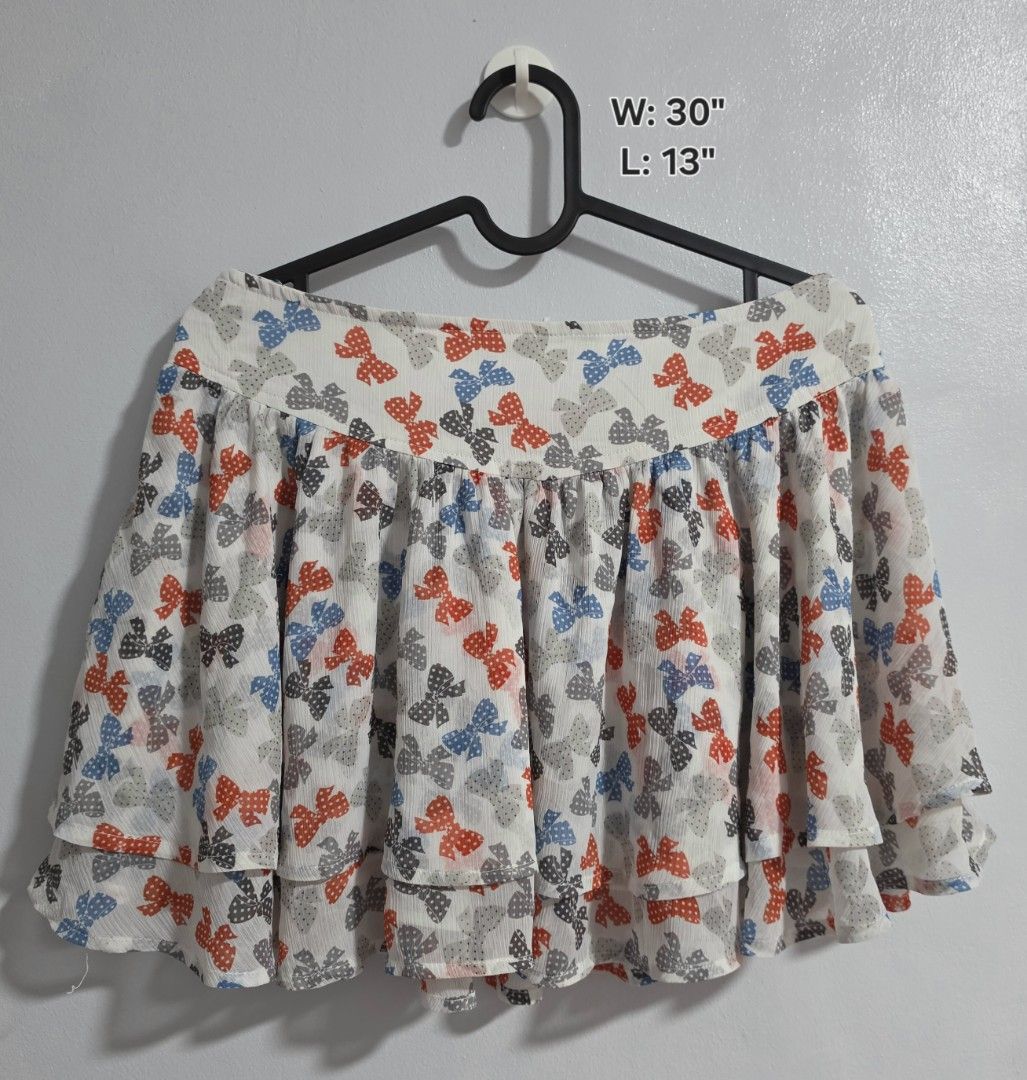 Etam Weekend Bow Pattern Layered Skirt Size 40 (Category: Skirts) located in Paranaque City. Submitted by franinnashop (Listing ID 1468361474, Image 1). Description: Declutter - Brand: Etam Weekend - Design: White skirt with red, blue, and grey bow prints, layered ruffle multi-tier design - Size: Tagged Size 40 (Width: 30 inches, Length: 13 inches) - Material: Lightweight chiffon-like fabric with side zipper closure - Style: Fun, playful, and eas