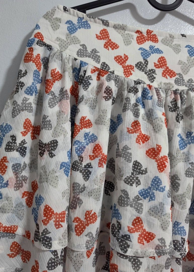 Etam Weekend Bow Pattern Layered Skirt Size 40 (Category: Skirts) located in Paranaque City. Submitted by franinnashop (Listing ID 1468361474, Image 2). Description: Declutter - Brand: Etam Weekend - Design: White skirt with red, blue, and grey bow prints, layered ruffle multi-tier design - Size: Tagged Size 40 (Width: 30 inches, Length: 13 inches) - Material: Lightweight chiffon-like fabric with side zipper closure - Style: Fun, playful, and eas