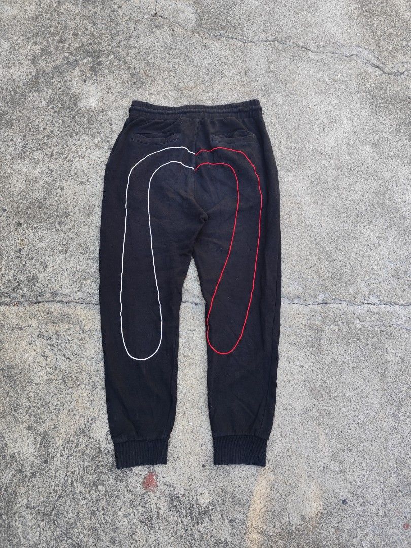 Evisu Black Sweatpants with Graphic Back Print (Category: Joggers) located in Lemery. Submitted by dailythriftin (Listing ID 1468434576, Image 3). Description: - Brand: Evisu - Material: Comfortable black cotton - Fit: Regular fit, ideal for casual wear - Design: Red embroidered logo on the front upper leg - Graphics: Large outline print on the back (white on left leg, red on right leg) - Features: Drawstring waist, ribbed cuffs, and practical sl