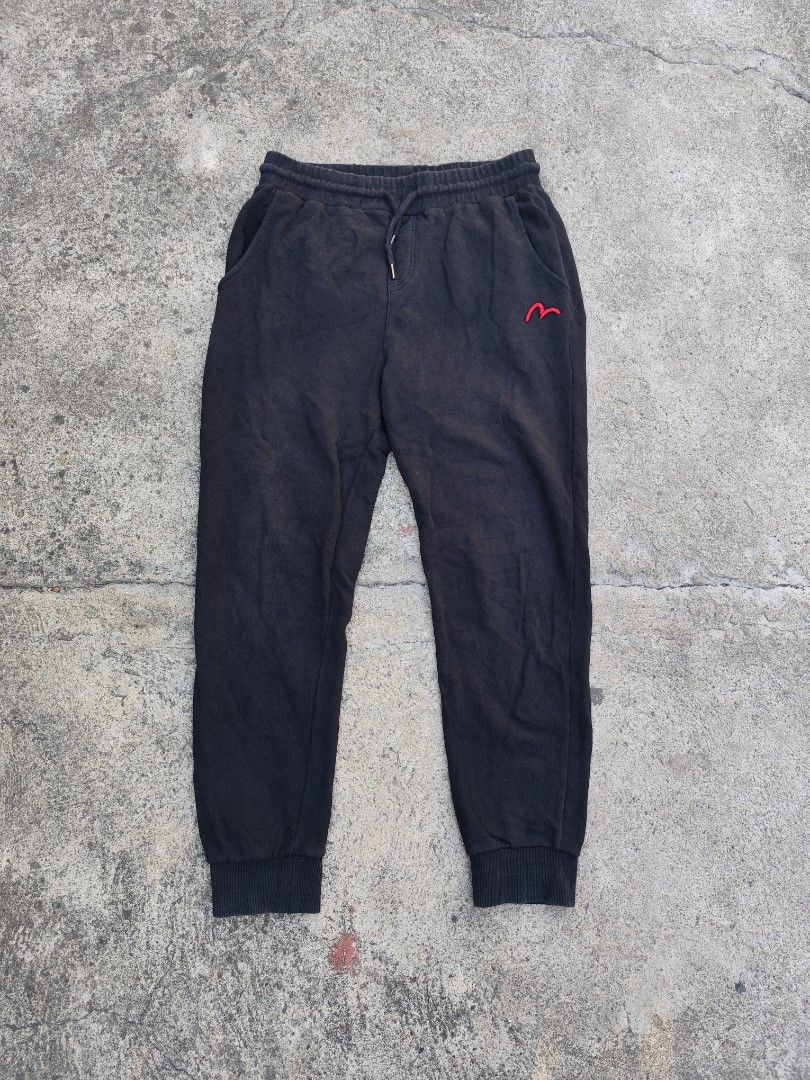 Evisu Black Sweatpants with Graphic Back Print (Category: Joggers) located in Lemery. Submitted by dailythriftin (Listing ID 1468434576, Image 1). Description: - Brand: Evisu - Material: Comfortable black cotton - Fit: Regular fit, ideal for casual wear - Design: Red embroidered logo on the front upper leg - Graphics: Large outline print on the back (white on left leg, red on right leg) - Features: Drawstring waist, ribbed cuffs, and practical sl