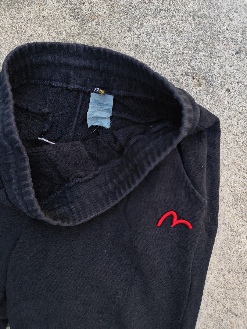 Evisu Black Sweatpants with Graphic Back Print (Category: Joggers) located in Lemery. Submitted by dailythriftin (Listing ID 1468434576, Image 2). Description: - Brand: Evisu - Material: Comfortable black cotton - Fit: Regular fit, ideal for casual wear - Design: Red embroidered logo on the front upper leg - Graphics: Large outline print on the back (white on left leg, red on right leg) - Features: Drawstring waist, ribbed cuffs, and practical sl