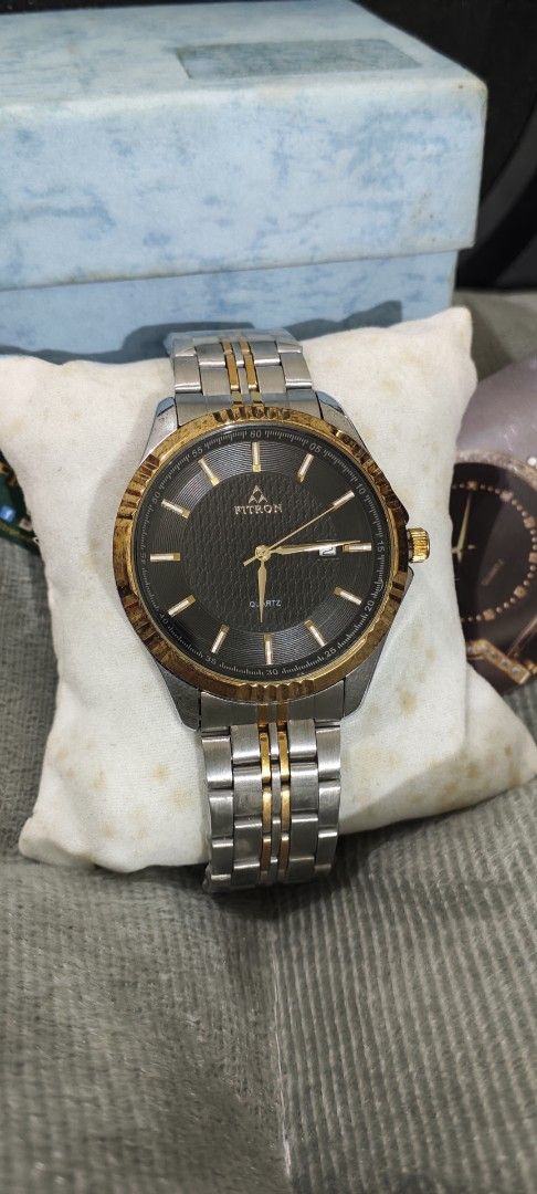 Fitron Quartz Two-Tone Men's Watch 9193M (Category: Men's Watches) located in Manila. Submitted by burgerpatti (Listing ID 1468462941, Image 2). Description: - Brand: Fitron Japan Quartz Watch (Model 9193M) - Design: Textured dark dial with gold bezel and date window at 3 o'clock - Strap: Two-tone silver and gold stainless steel bracelet - Build: Stainless steel back, water resistant - Inclusions: Complete with original blue box, tags, and produc