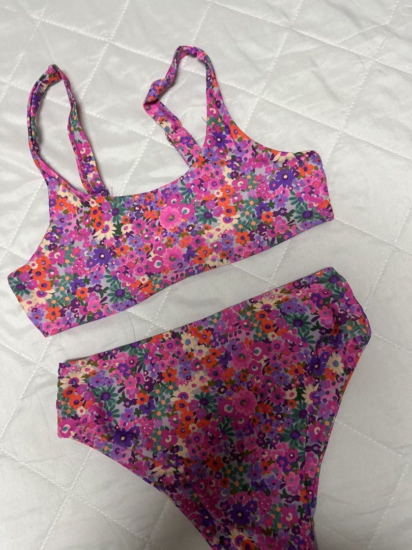 Floral Print Two-Piece Bikini High-Waisted (Category: Bikinis & Swimsuits) located in Valenzuela. Submitted by prelovedbyramsie (Listing ID 1468409508, Image 2). Description: - Style: Two-piece bikini set with high-waisted bottoms and a scoop neck crop top - Design: Vibrant floral pattern in purple, pink, and orange - Features: Adjustable straps for a customized fit and flattering cut - Material: Stretchy, comfortable swim fabric - Condition: Cle