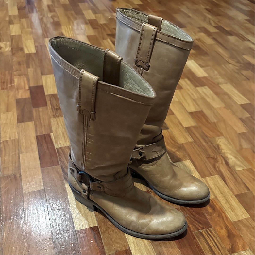 Frye Tan Camel Brown Leather Mid-Calf Harness Boots (Category: Boots) located in Pasig City. Submitted by ratatoubrie (Listing ID 1468374895, Image 3). Description: FRYE 12R Harness (Model 3470105 COG) Genuine vegetable tanned leather unlined interior Made in Mexico Size: Women's 6.5 B Tan leather boots, mid-calf height. Classic harness strap detail with metal rings around the ankles. Pull-on style with dual side pull tabs. Sturdy stacked heel an