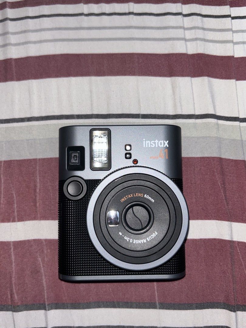 Fujifilm Instax Mini 41 Instant Camera (Category: Cameras) located in Manila. Submitted by 444vincci (Listing ID 1468487002, Image 1). Description: - Model: Fujifilm Instax Mini 41 Instant Camera - Color: Sleek Dark Grey with a textured grip handle - Lens: 60mm Instax lens (0.3m to infinity focus range) - Key Features: Built-in flash, close-up mode, and easy switch operation - Display: Rear film counter display - Power: Battery-operated - Conditi